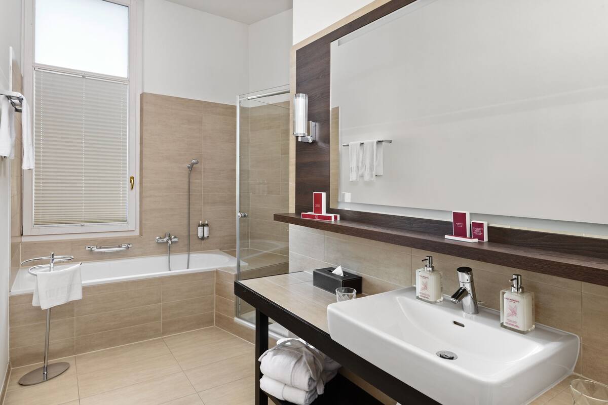 A modern bathroom with a bathtub, a large mirror, and a vanity with a sink.