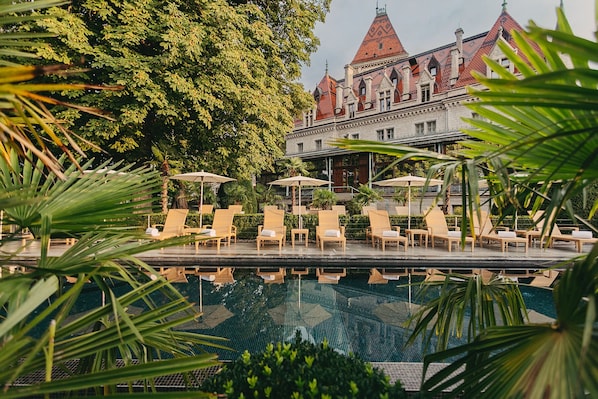 Una piscina al aire libre, sillones reclinables de piscina