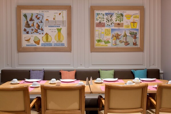 A dining area with tables set for a meal, featuring a wall with educational posters about onions and table setting.