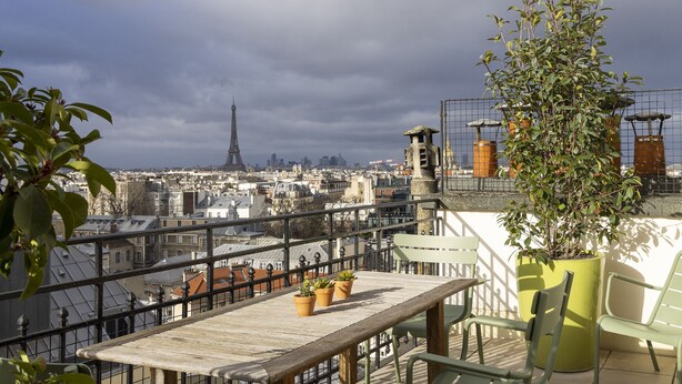 A rooftop terrace with a view of the Eiffel Tower, potted plants, and a wooden table. - Hôtel Le Littré (Paris)