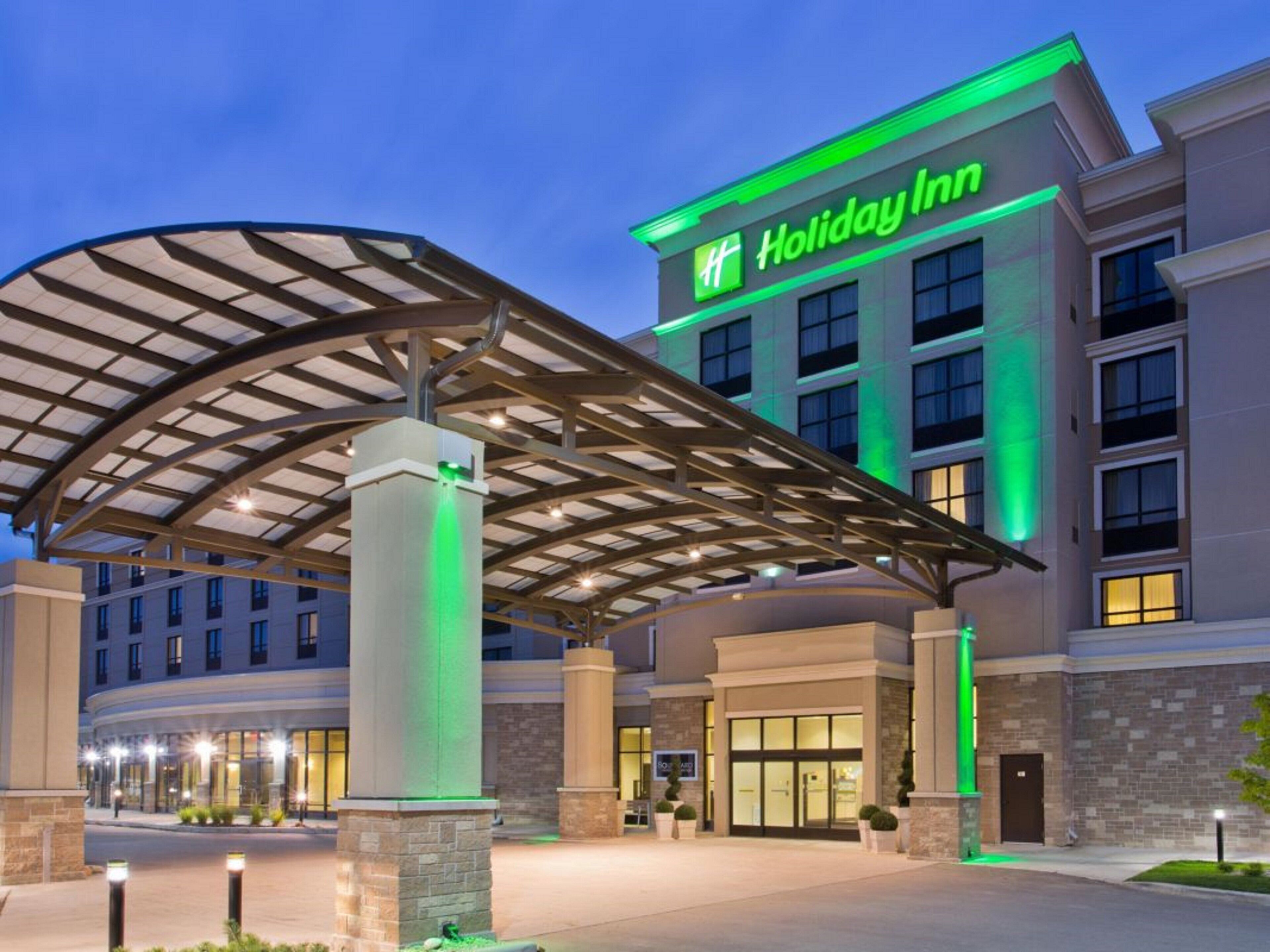 Un hôtel Holiday Inn doté d’une entrée couverte, de plusieurs étages et d’une façade bien éclairée.