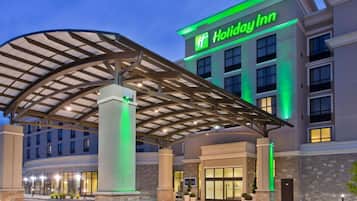 Un hôtel Holiday Inn doté d’une entrée couverte, de plusieurs étages et d’une façade bien éclairée.
