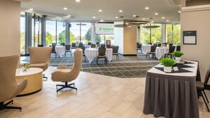 A hotel conference room with round tables, chairs, and a view of a lake. - Holiday Inn Richland on the River by IHG (Richland)