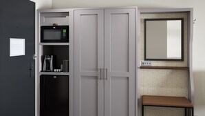 A room with a wardrobe, a microwave, a coffee machine, and a small bench. - Holiday Inn Richland on the River by IHG (Richland)