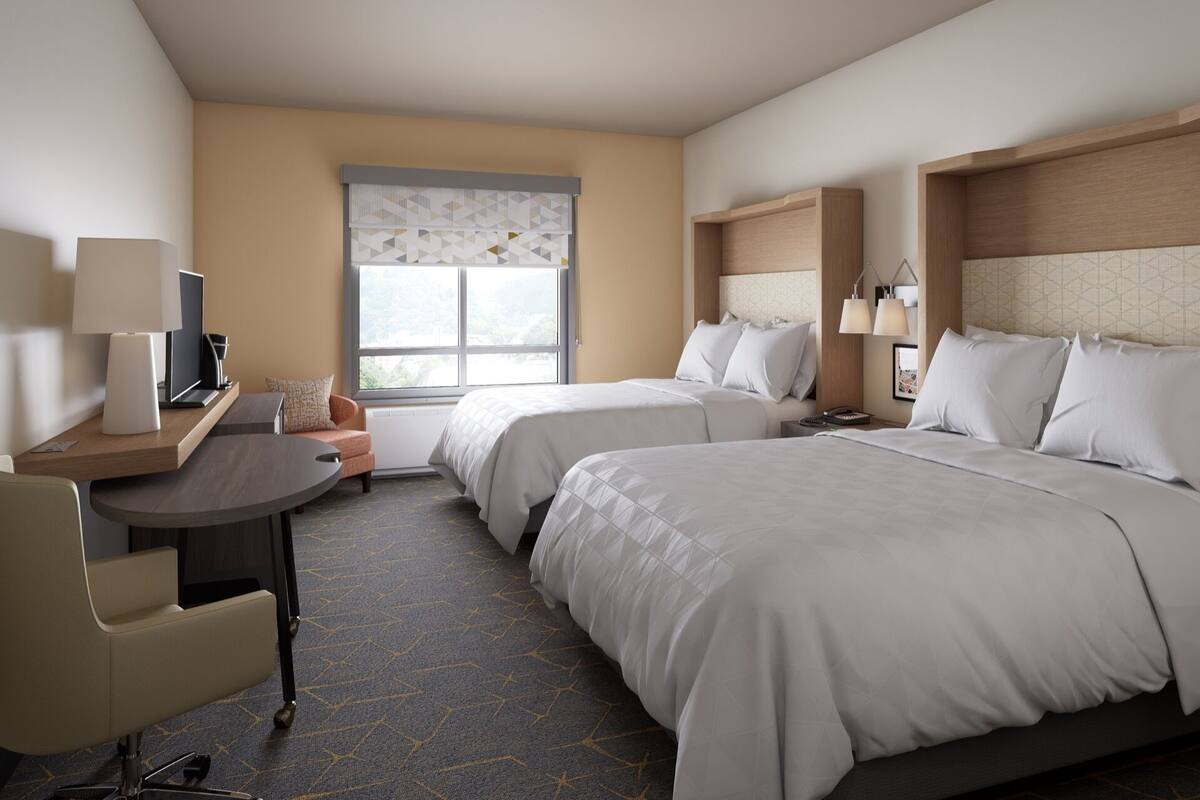 Ein Hotelzimmer mit zwei Betten, einem Schreibtisch mit Stuhl, einem Fernseher und einem Fenster mit Blick.