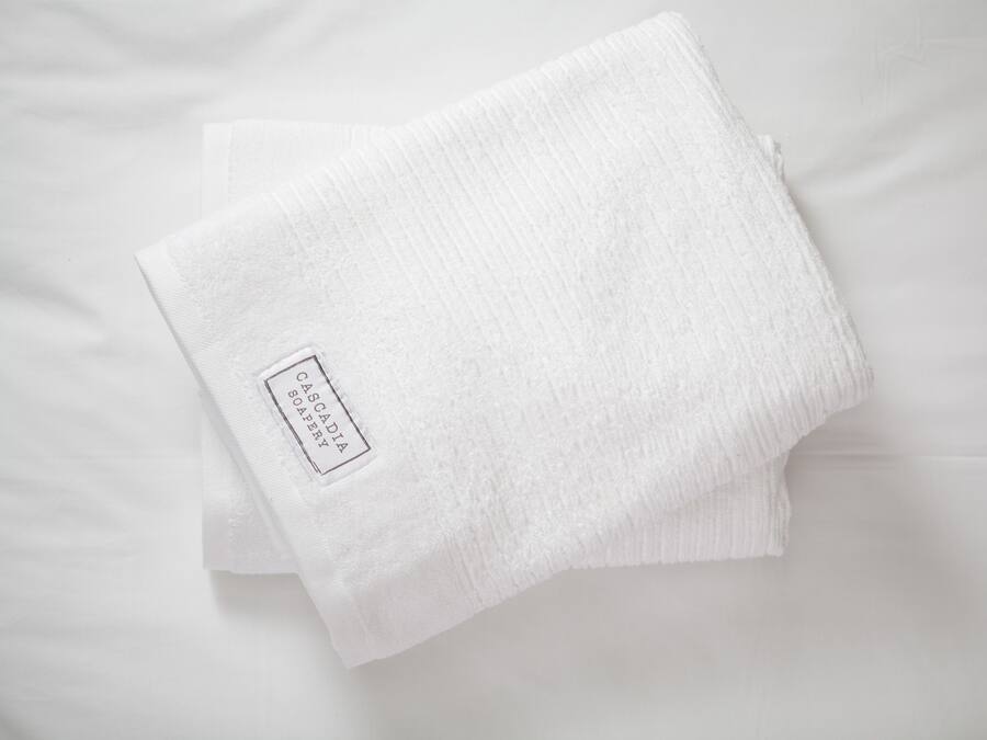A folded white towel with a label on a white surface.