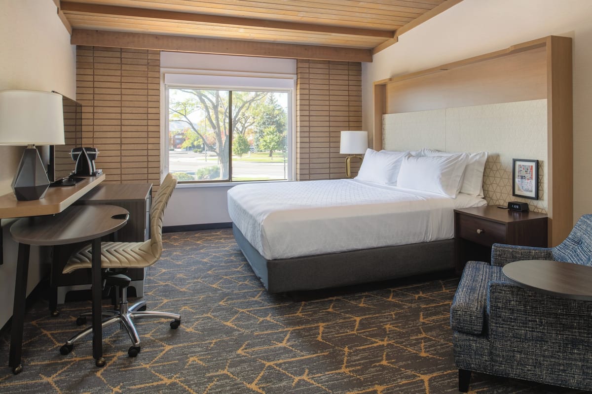 Ein Hotelzimmer mit Bett, Schreibtisch, Stuhl und Blick ins Freie.