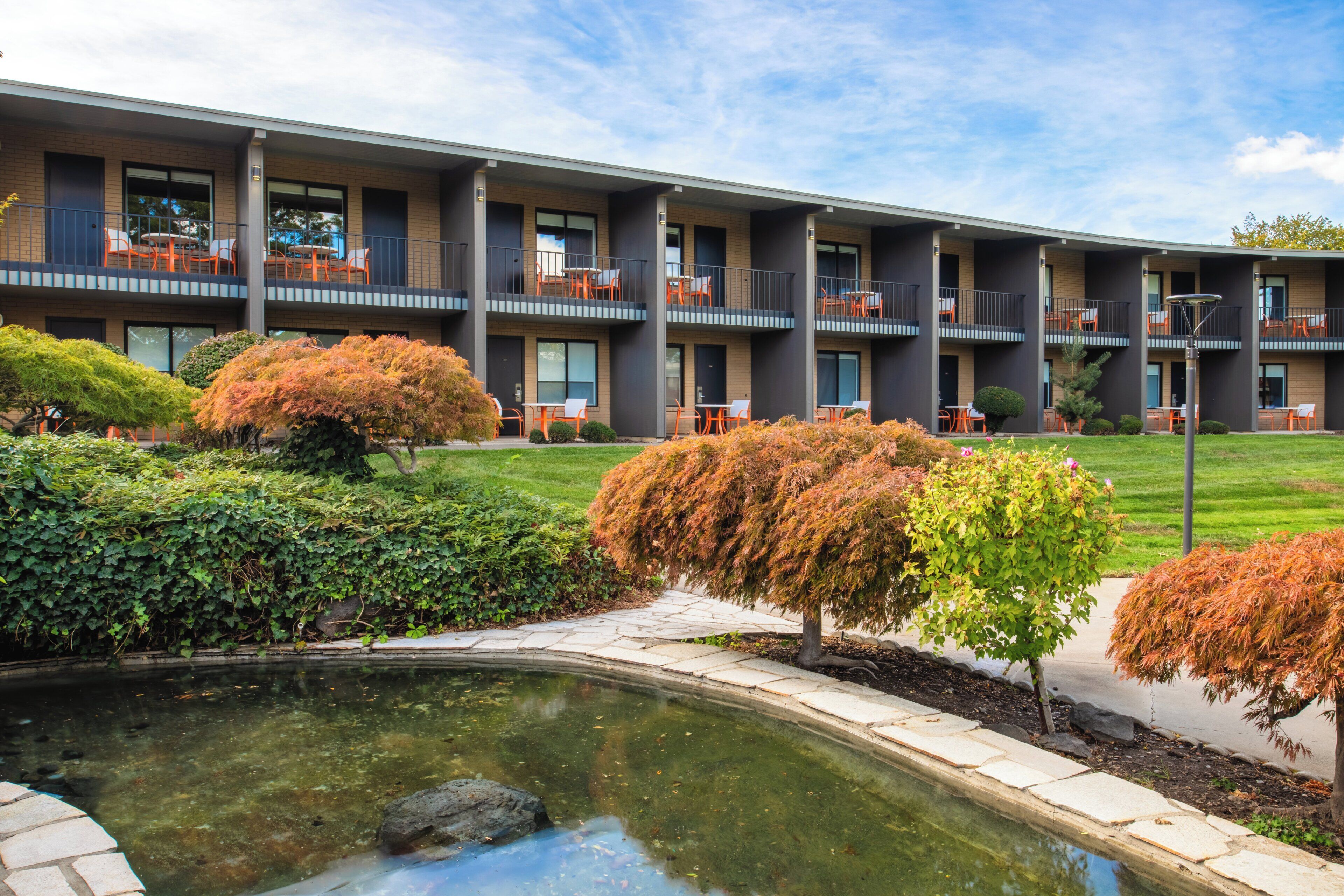 A multi-story building with outdoor seating areas and a small pond.