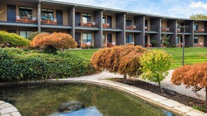 A multi-story building with outdoor seating areas and a small pond. - Holiday Inn Richland on the River by IHG (Richland)