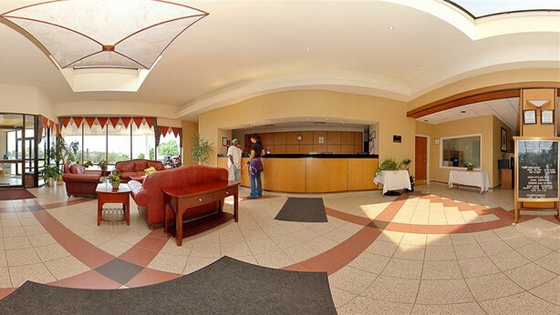 Vestíbulo de hotel con una recepción, zona de estar y vistas al exterior.