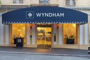 A hotel entrance with a dark awning displaying the name 'WYNDHAM'.