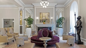 A luxurious living room with a plush red sofa, elegant armchairs, a round coffee table, and a fireplace. - Club Wyndham Canterbury (San Francisco)