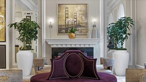 A luxurious lobby with a large painting of the Golden Gate Bridge, a fireplace, and elegant seating arrangements. - Club Wyndham Canterbury (San Francisco)