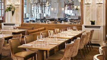 Un restaurant doté de nombreuses tables et chaises, d’une cheminée et de lustres.