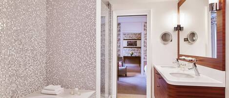 Un baño moderno con pared de mosaicos, una bañera grande y un tocador con espejo.