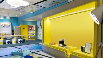 A brightly colored children's play area with a yellow wall, a white ceiling with star decorations, and a blue carpet with animal prints.