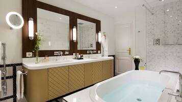 Een moderne badkamer met een grote spiegel, twee wasbakken, een bad en een douche.