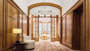 Een luxe lobby met een centrale kroonluchter, een bank en een bordje voor Guerlain Spa.
