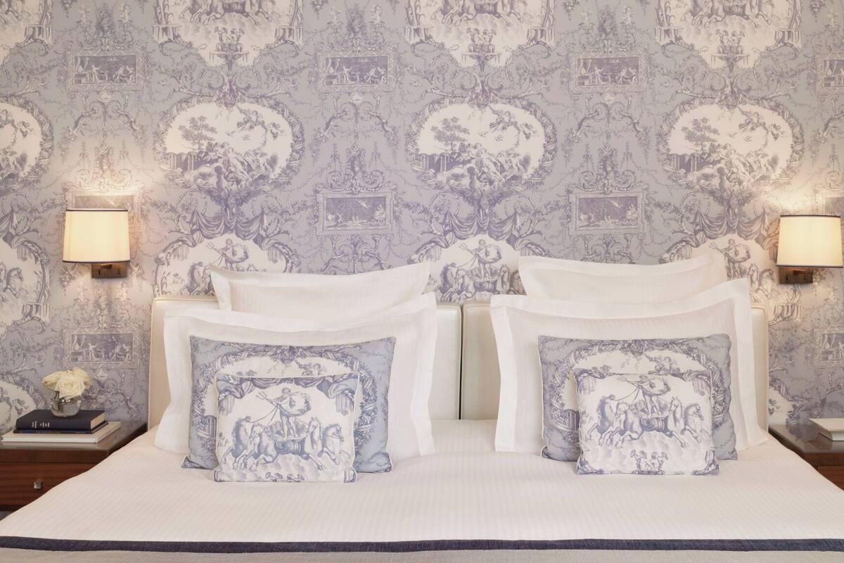 A bedroom with a large bed, two nightstands, and a wall with a detailed pattern.