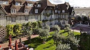 Een traditionele Europese binnenplaats met een gebouw met rieten dak, een witte hek en een verzorgd gazon.