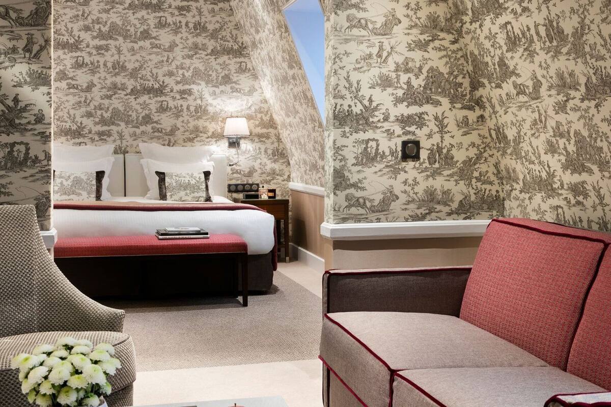 A hotel room with a bed, a sofa, a chair, and a nightstand.