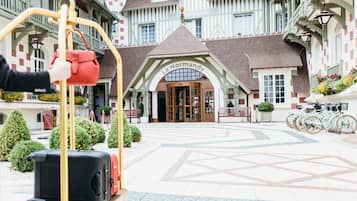 Enter Le Normandy through its elegant arched doorway, surrounded by lush hedges and bicycles.