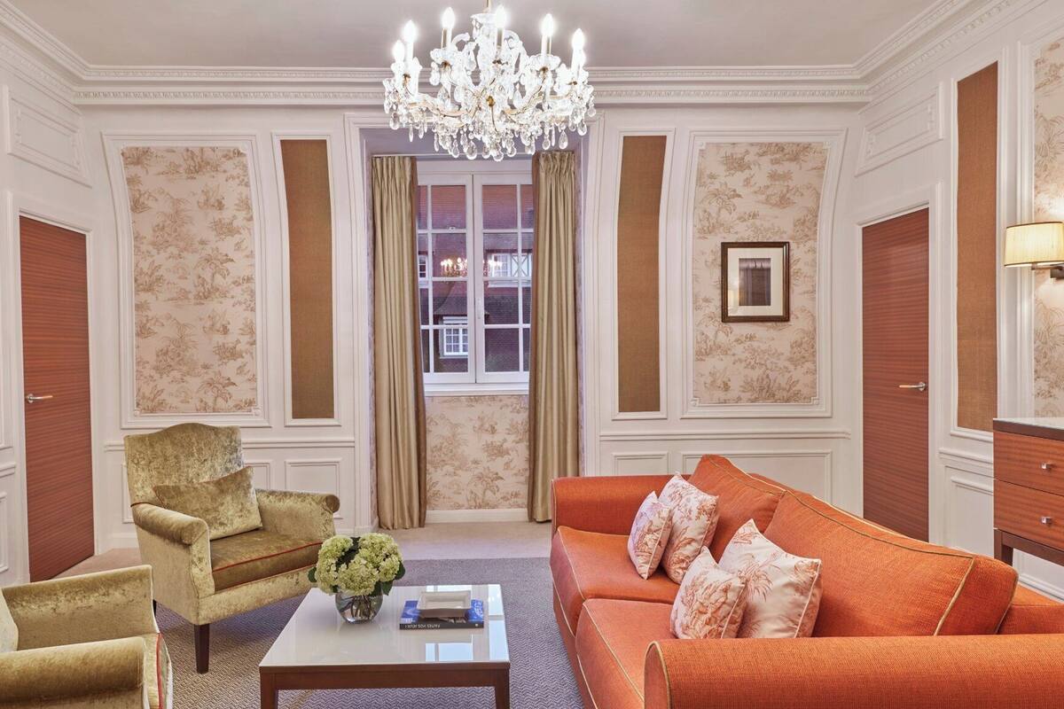 A room with a chandelier, a sofa, a chair, and a coffee table.