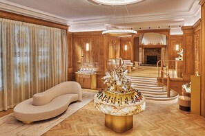 Ein luxuriöses Interieur mit einer gebogenen Couch, einem Marmortisch und einer Treppe zu einem Kamin.