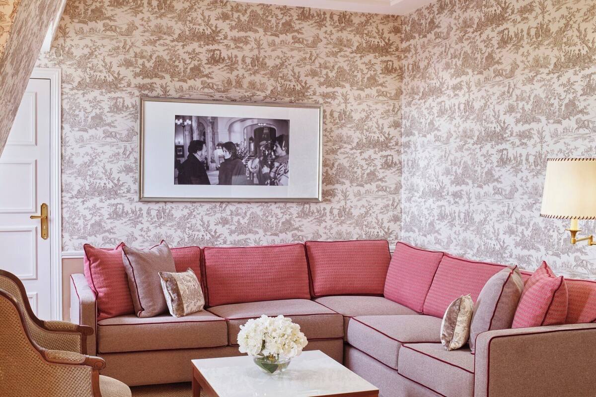 A living room with a sectional sofa, a chair, a coffee table with a vase of flowers, and a framed picture on the wall.