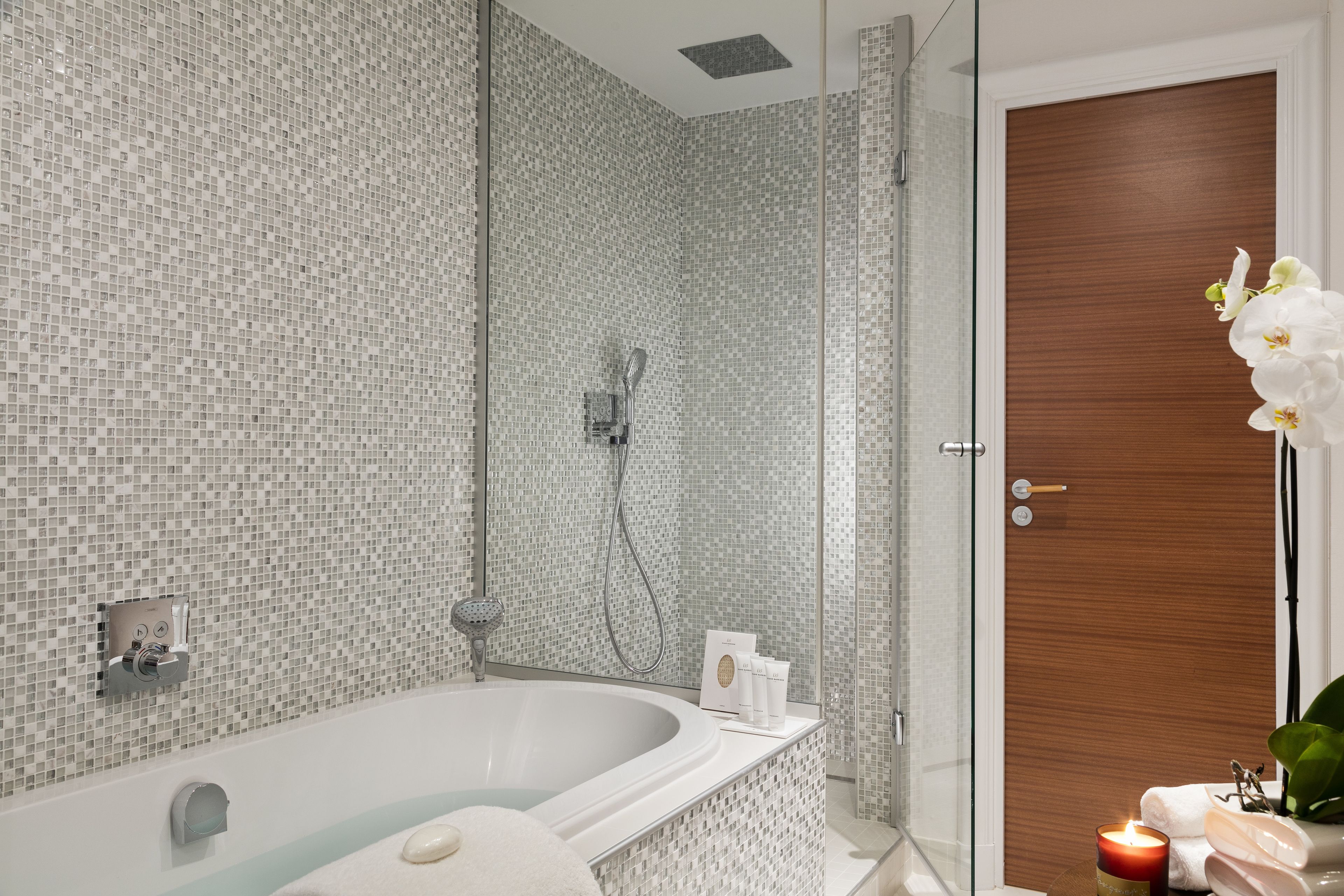 Un baño moderno con una bañera independiente, un box de ducha de vidrio y una puerta de madera.