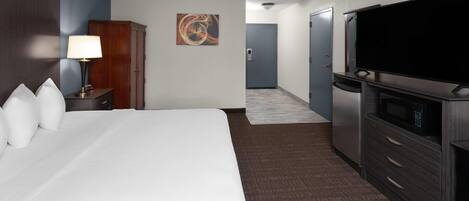 A hotel room with a large bed, a TV, a desk, and a wardrobe.