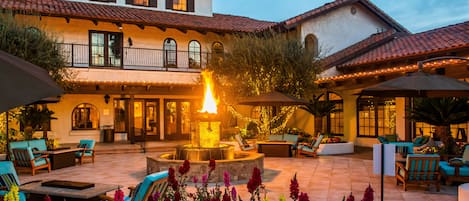 Un patio con una chimenea, mobiliario exterior y una variedad de flores.