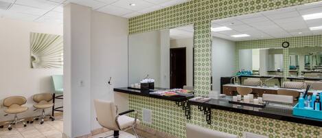 Ein moderner Salon mit einem schwarzen Empfangstresen, mehreren Sitzgelegenheiten und einem großen Spiegel.