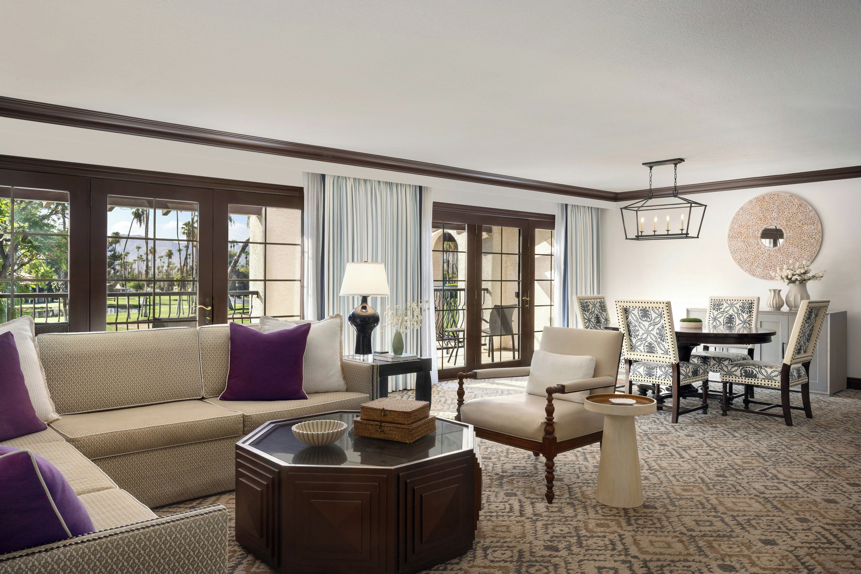 A spacious living room with a sofa, armchairs, a coffee table, and a dining area with chairs and a table.