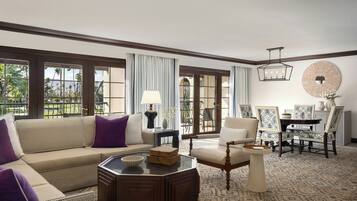 A spacious living room with a sofa, armchairs, a coffee table, and a dining area with chairs and a table.