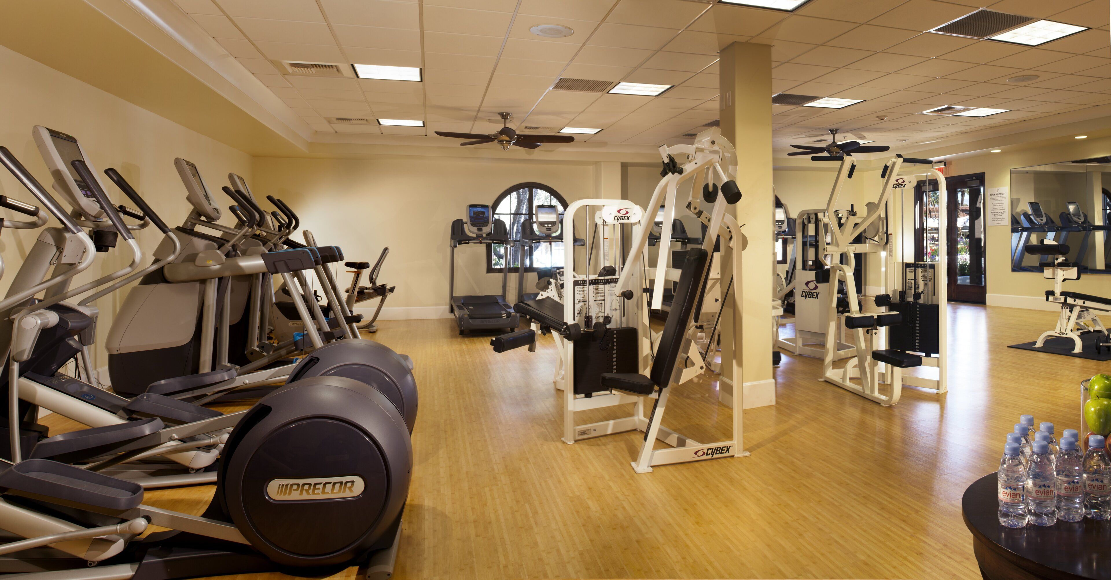 Une salle de sport équipée de divers appareils d’exercice, notamment des tapis de course, des vélos elliptiques et des appareils de musculation.