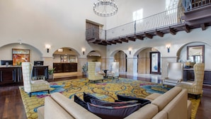A spacious lobby with a high ceiling, a chandelier, and a balcony with wrought iron railings. - Omni Rancho Las Palmas Resort & Spa (Rancho Mirage)