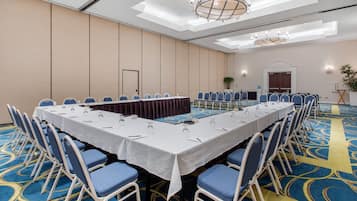 Una sala de conferencias con una larga mesa, sillas azules y una alfombra estampada.