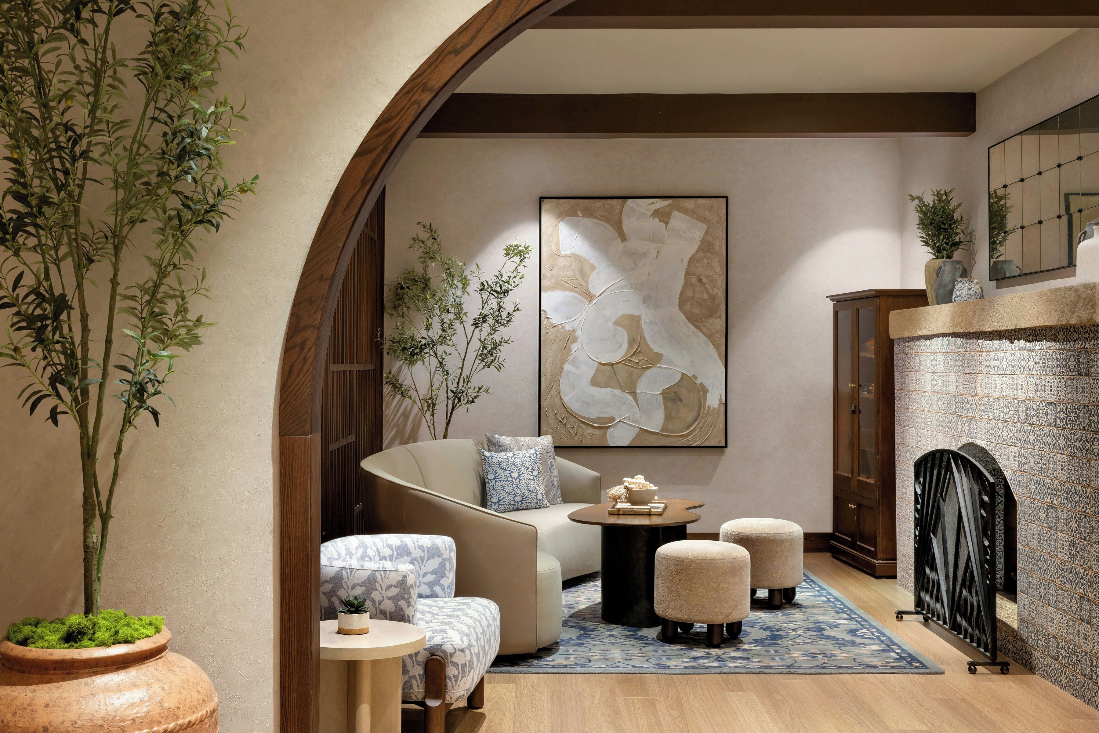Ein modernes Interieur mit einer Couch, Hocker, einem Couchtisch und einem großen abstrakten Gemälde.