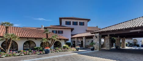 A courtyard with a tiled roof, a building with arched windows, and a fountain.