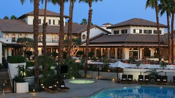 Een resort met een zwembad, palmbomen en buitenzitplaatsen.