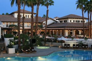 A resort with a swimming pool, palm trees, and outdoor seating areas.