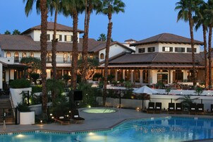 Un resort con piscina, palmeras y zonas de estar al aire libre.