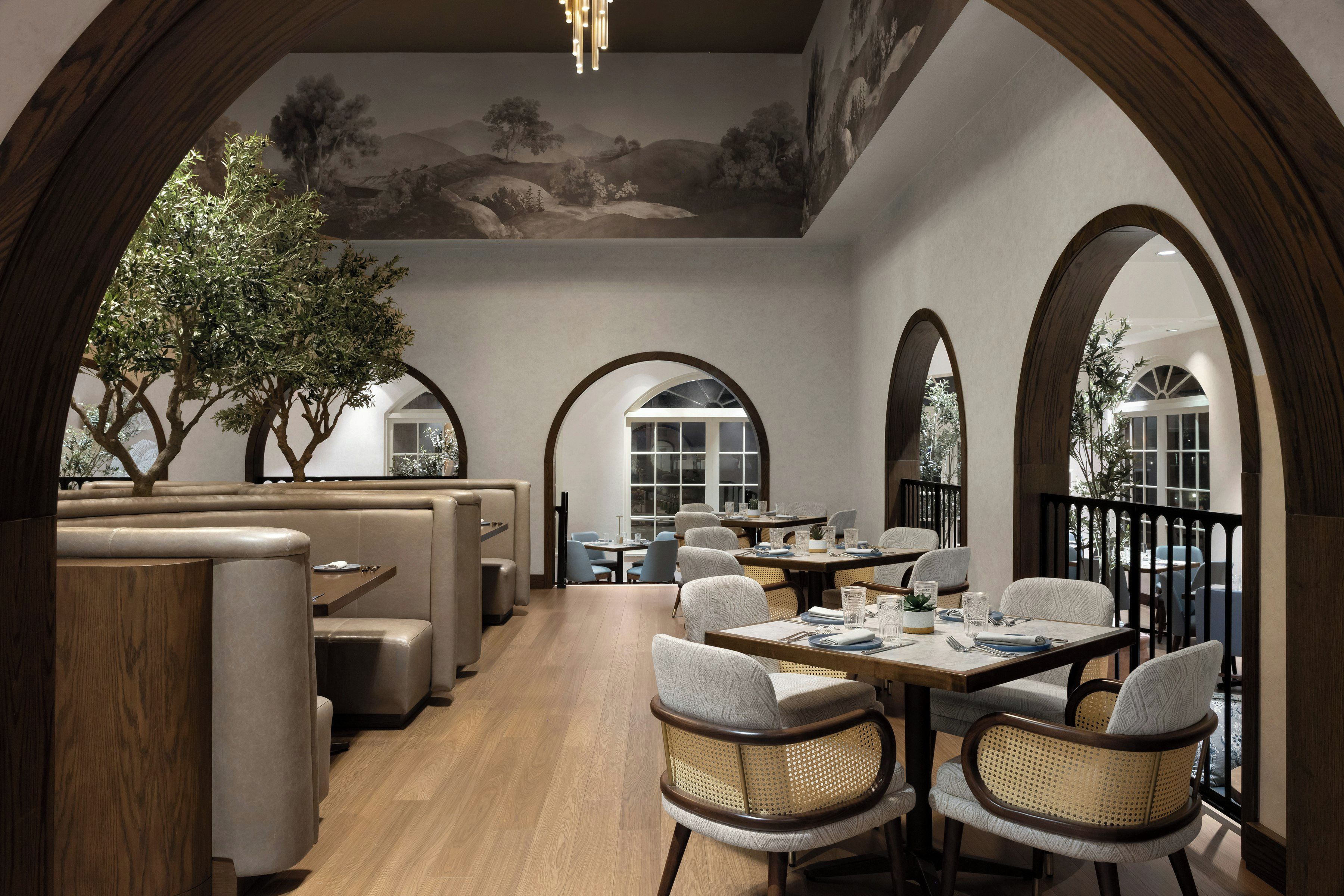 A restaurant with high wooden arches, cushioned seating, and a mural on the ceiling.