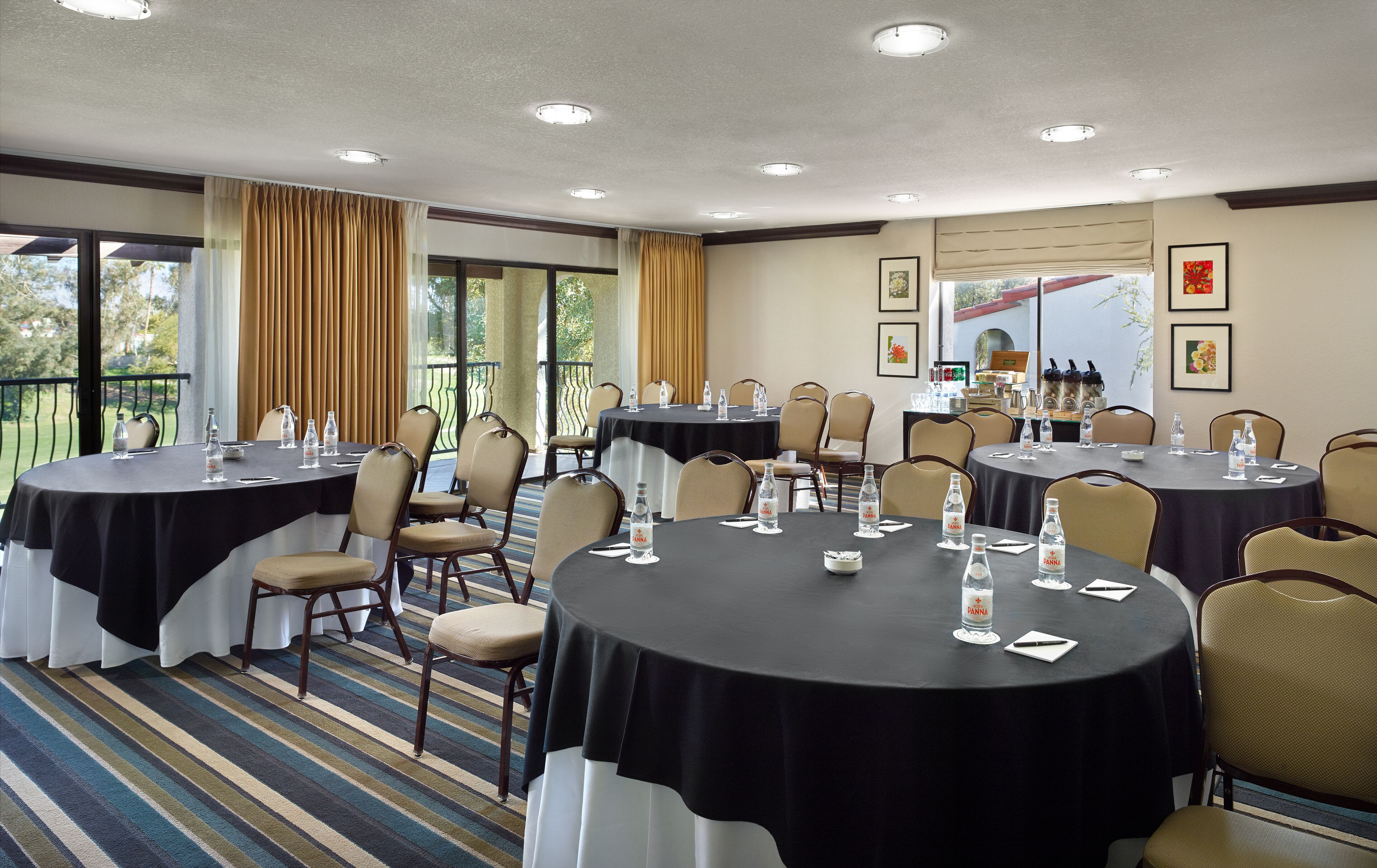 A conference room with round tables, chairs, and water bottles.