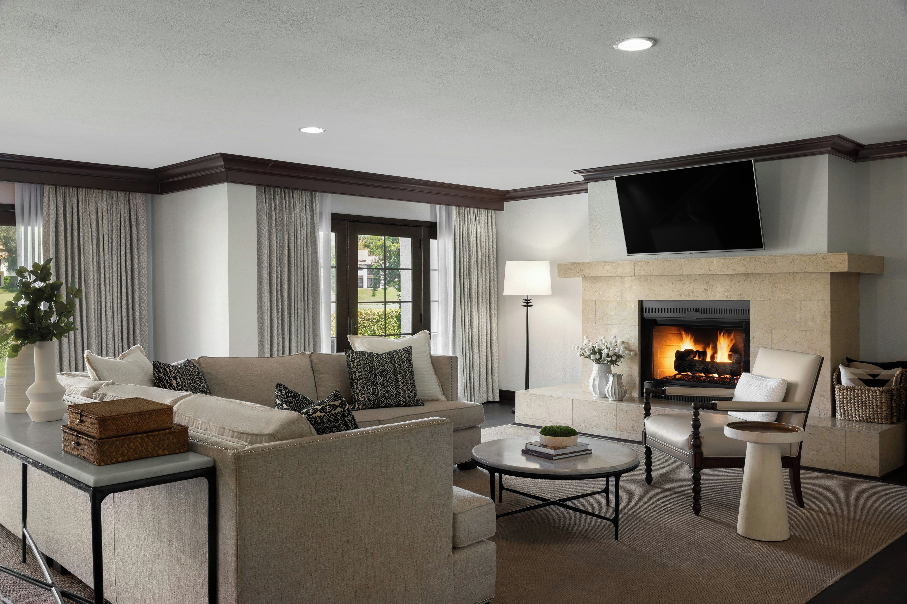 A modern living room with a fireplace, comfortable seating, and a flat-screen TV mounted above the fireplace.