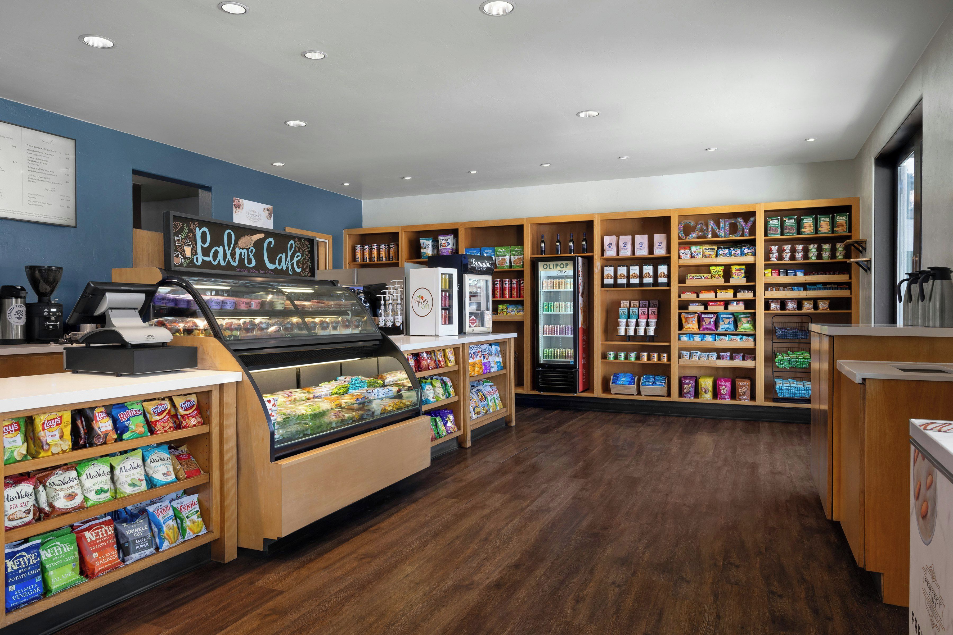 Un negozio di alimentari con banco gastronomia, vetrina refrigerata e scaffali pieni di snack e bevande.