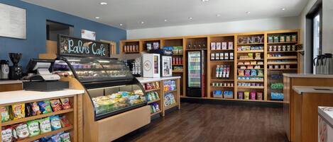 Un negozio di alimentari con banco gastronomia, vetrina refrigerata e scaffali pieni di snack e bevande.