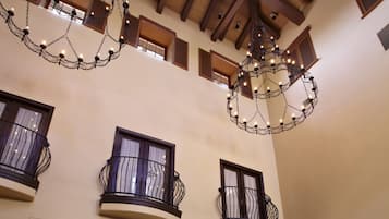 Un vestíbulo amplio con techos altos, una araña de cristal y una alfombra estampada.