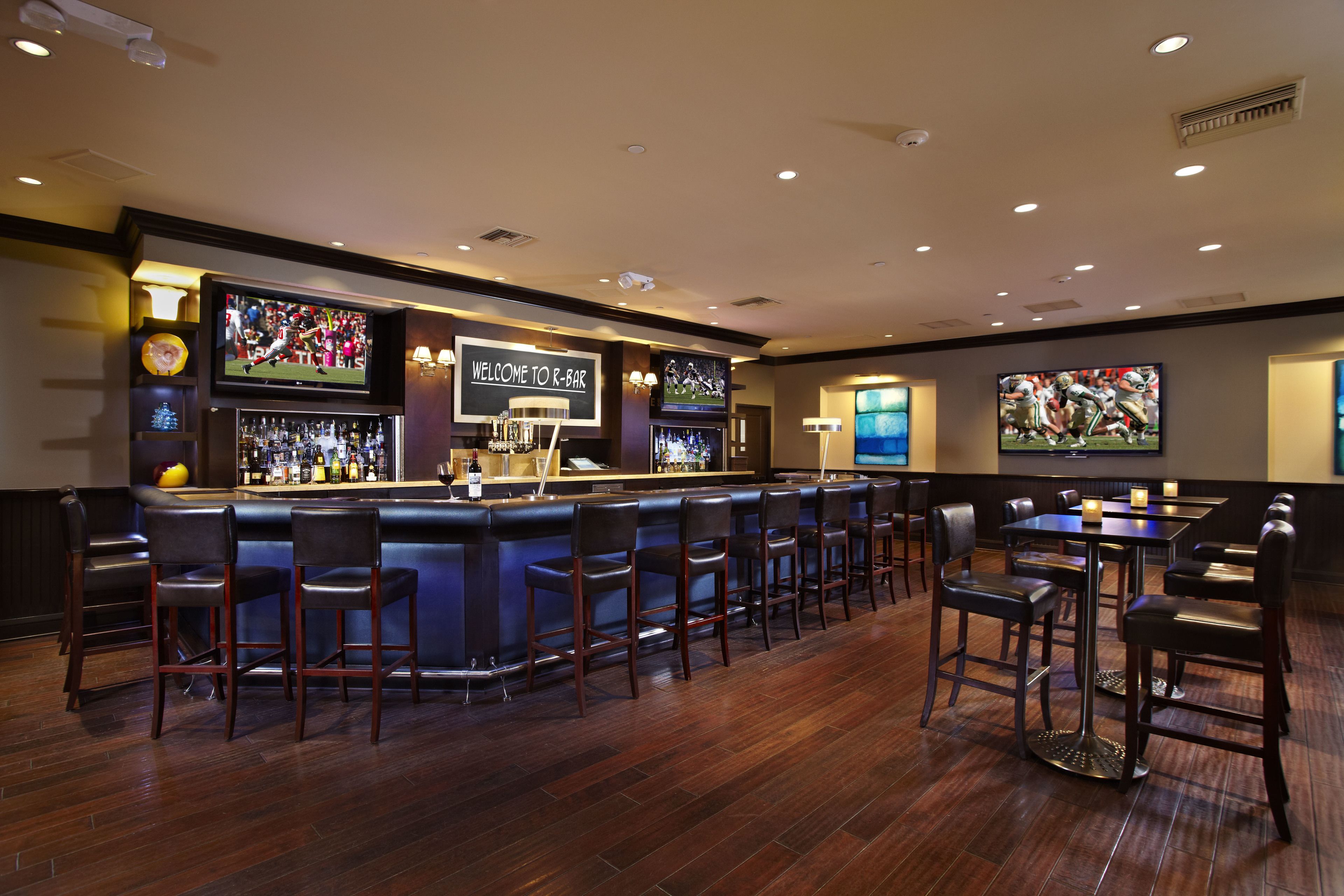 A bar area with a counter, bar stools, and tables.